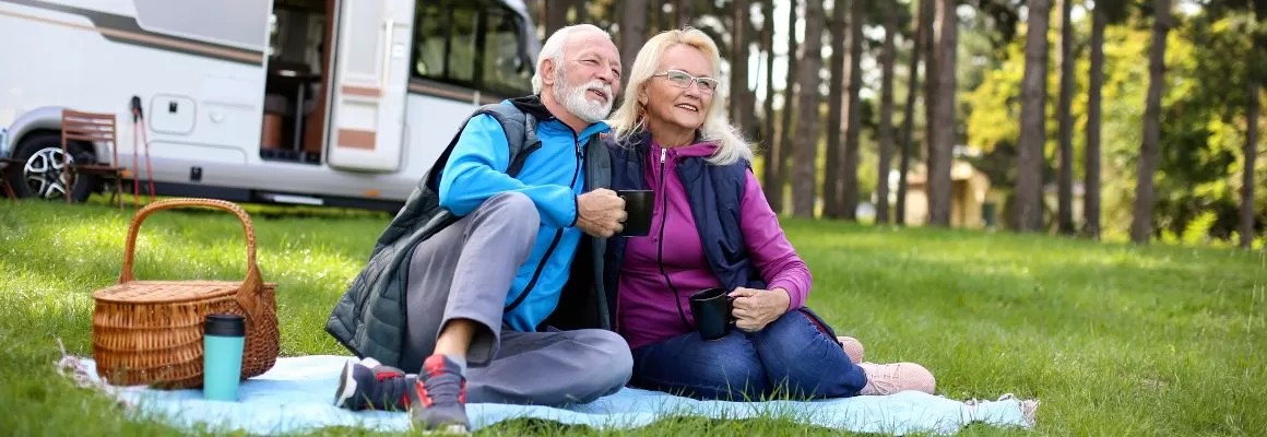 older couple drinking coffee outside camper