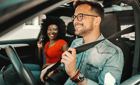 Young couple sitting in a car and fastening seat belts.