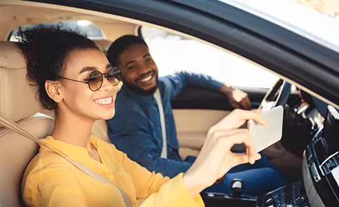 woman taking selfie with man in new car