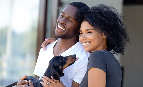 Happy couple standing outdoors holding dachshund puppy