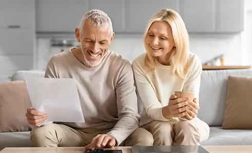 mature couple looking over financial statements with calculator in home setting