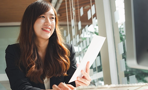 Female finance worker holding papers and smiling