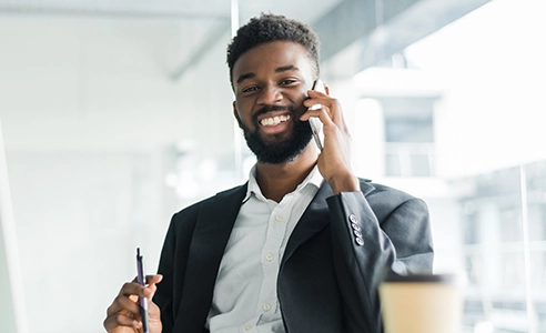 young professional man talking on cell phone and holding pen